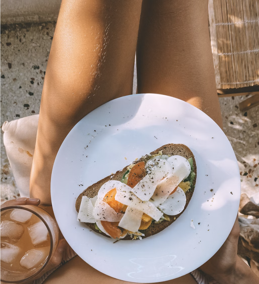 Fresh healthy foods including salmon, avocado, berries, and leafy greens displayed on a kitchen counter, representing nutrition for glowing skin health.